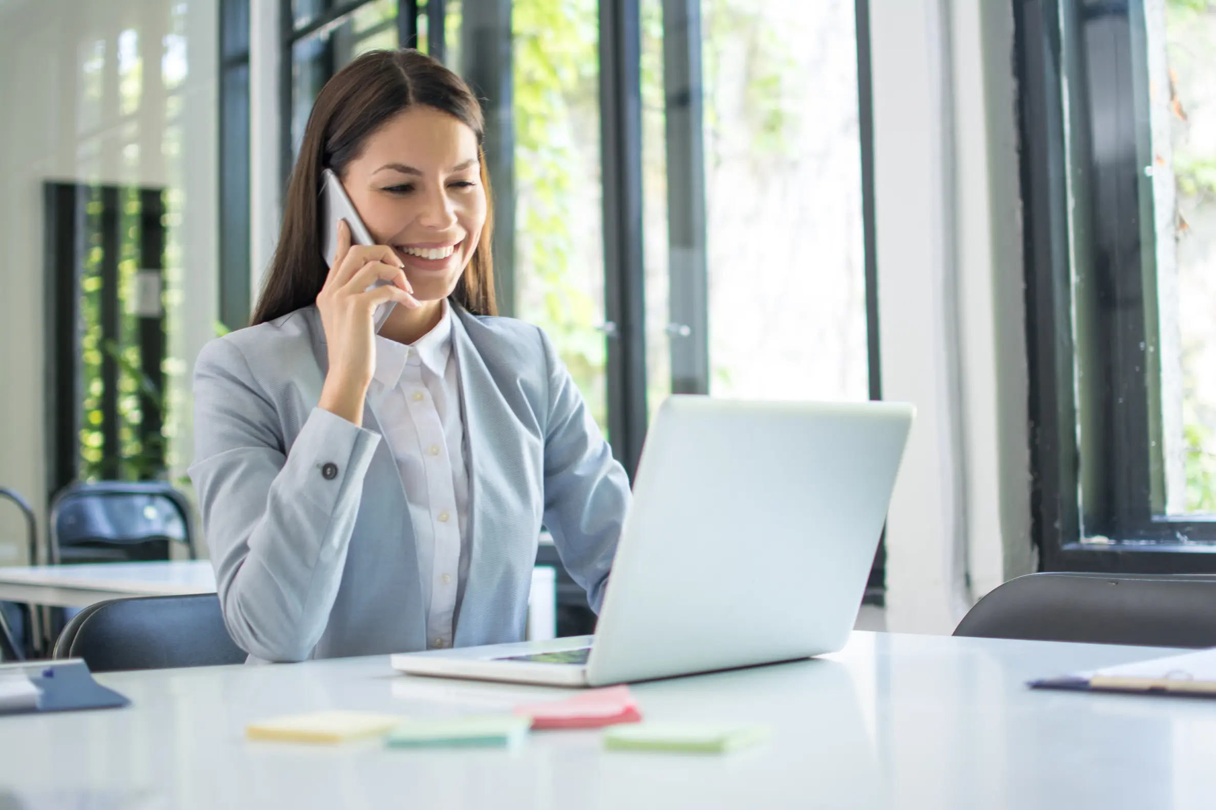 Professional business owner on phone call working on laptop considering serving as own registered agent for LLC or corporation