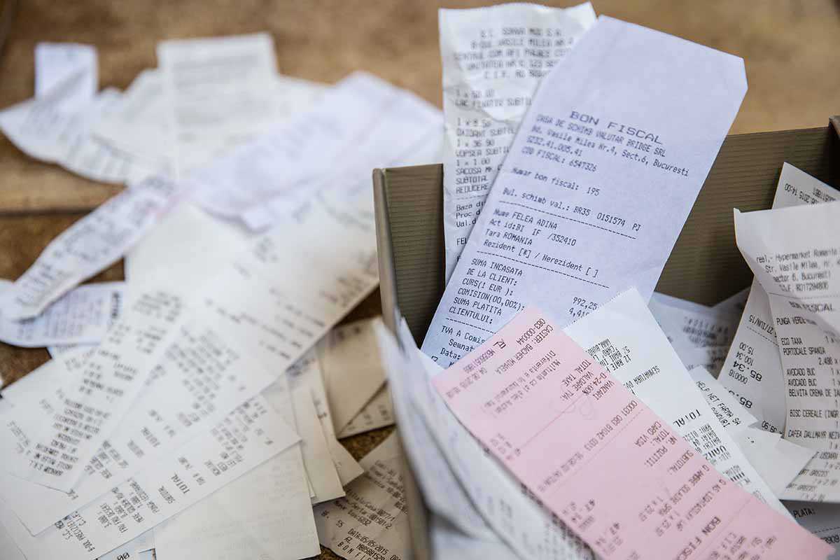 A pile of receipts lying on a desk and in a box