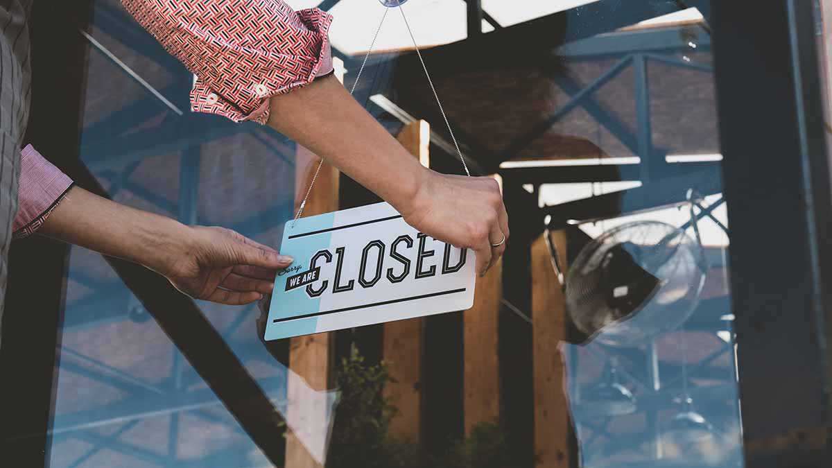 A business owner hangs a closed sign on the business door